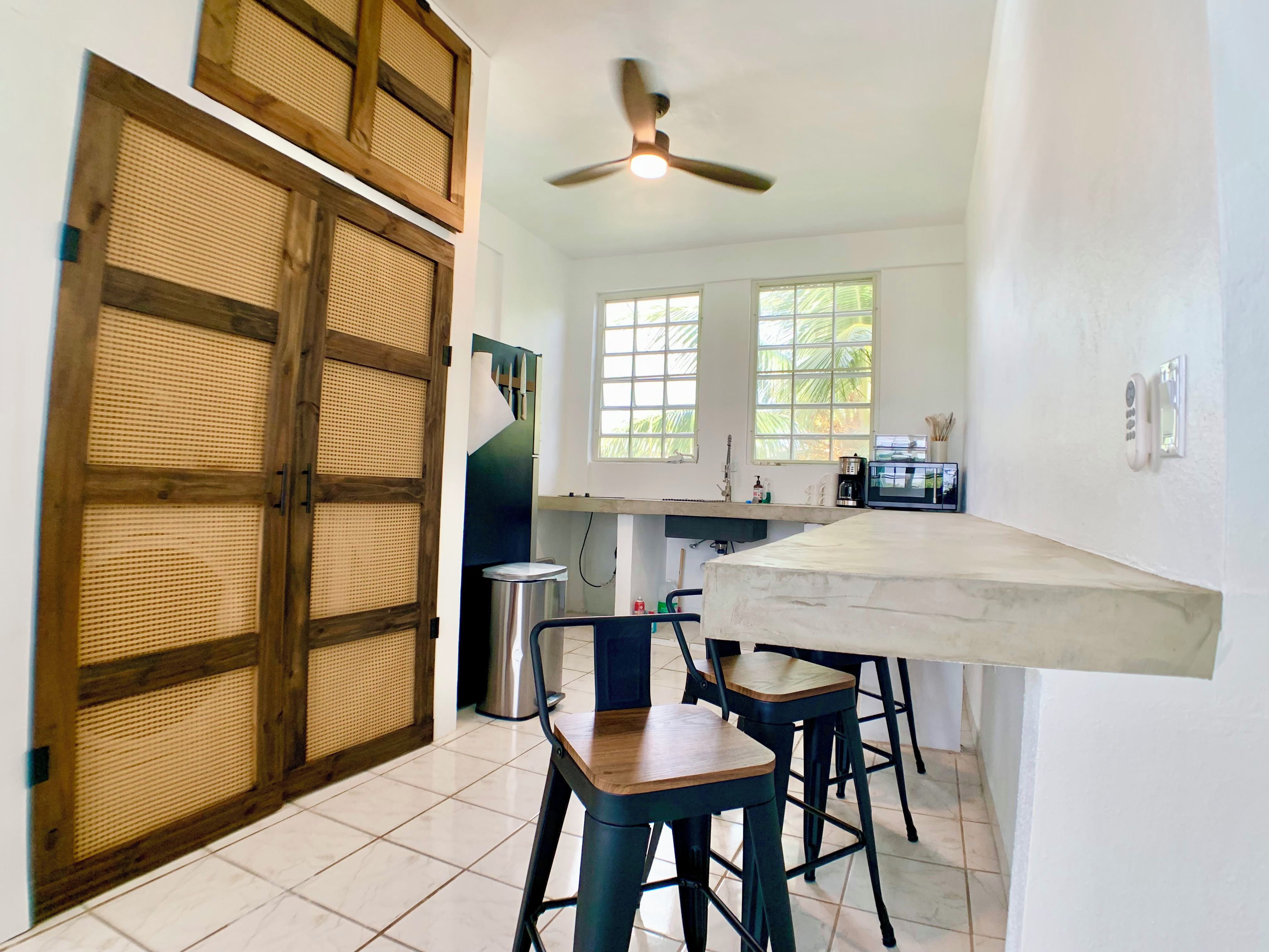 Cozinha com porta de madeira, ventilador de teto e janela.