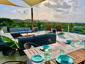 Een terras buiten met zit- en eethoek, met uitzicht op een mooi landschap.