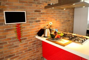 A kitchen with a brick wall, a gas stove, a coffee maker, and a decorative plant. - Casa Muntú - La Candelaria (Bogotá)