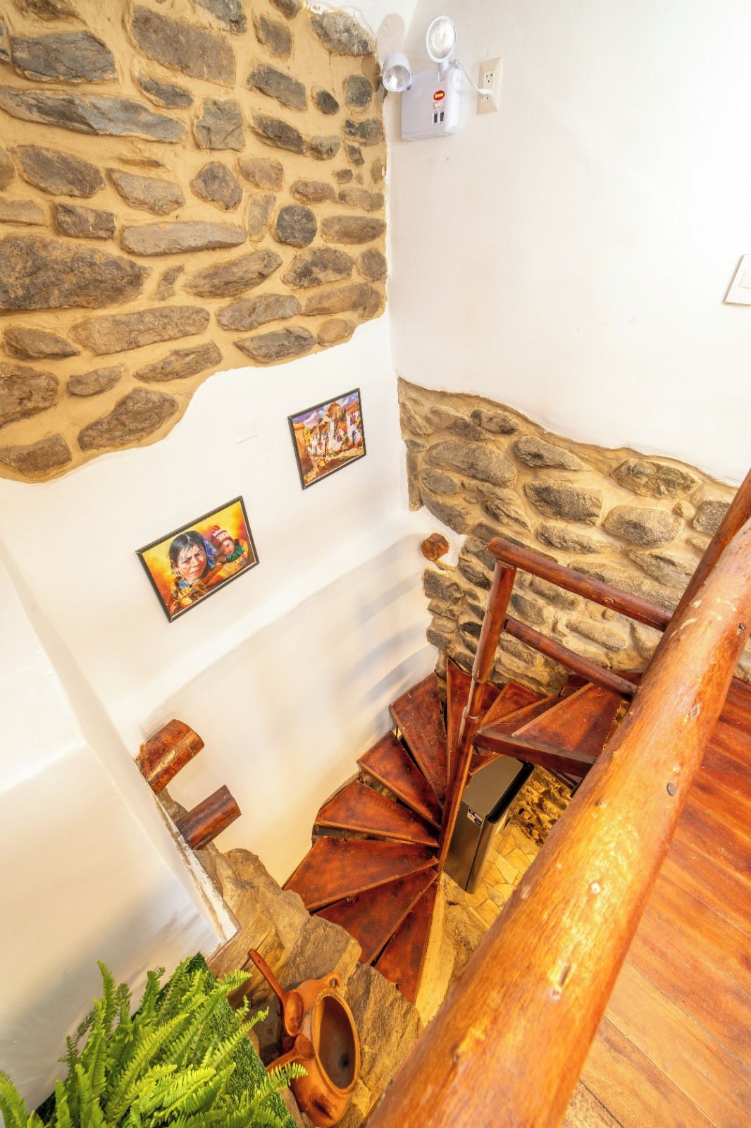 A spiral staircase with stone walls and wooden steps, leading to a higher floor.