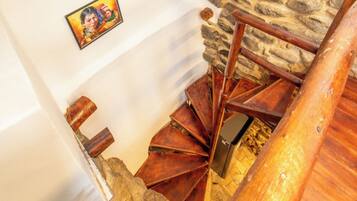 A spiral staircase with stone walls and wooden steps, leading to a higher floor.