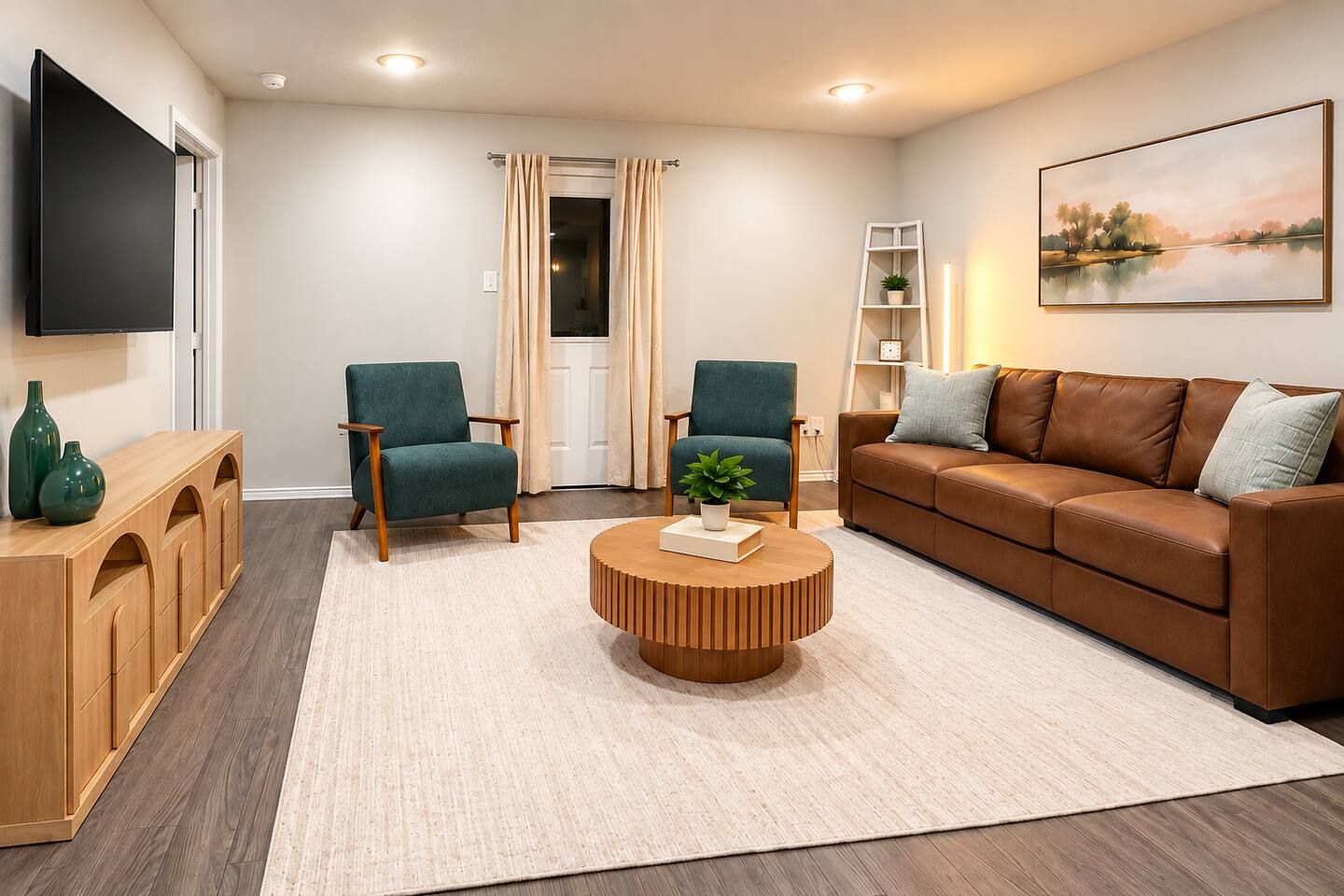A modern living room with a brown leather sofa, two teal armchairs, a wooden coffee table, and a flat-screen TV mounted on the wall.