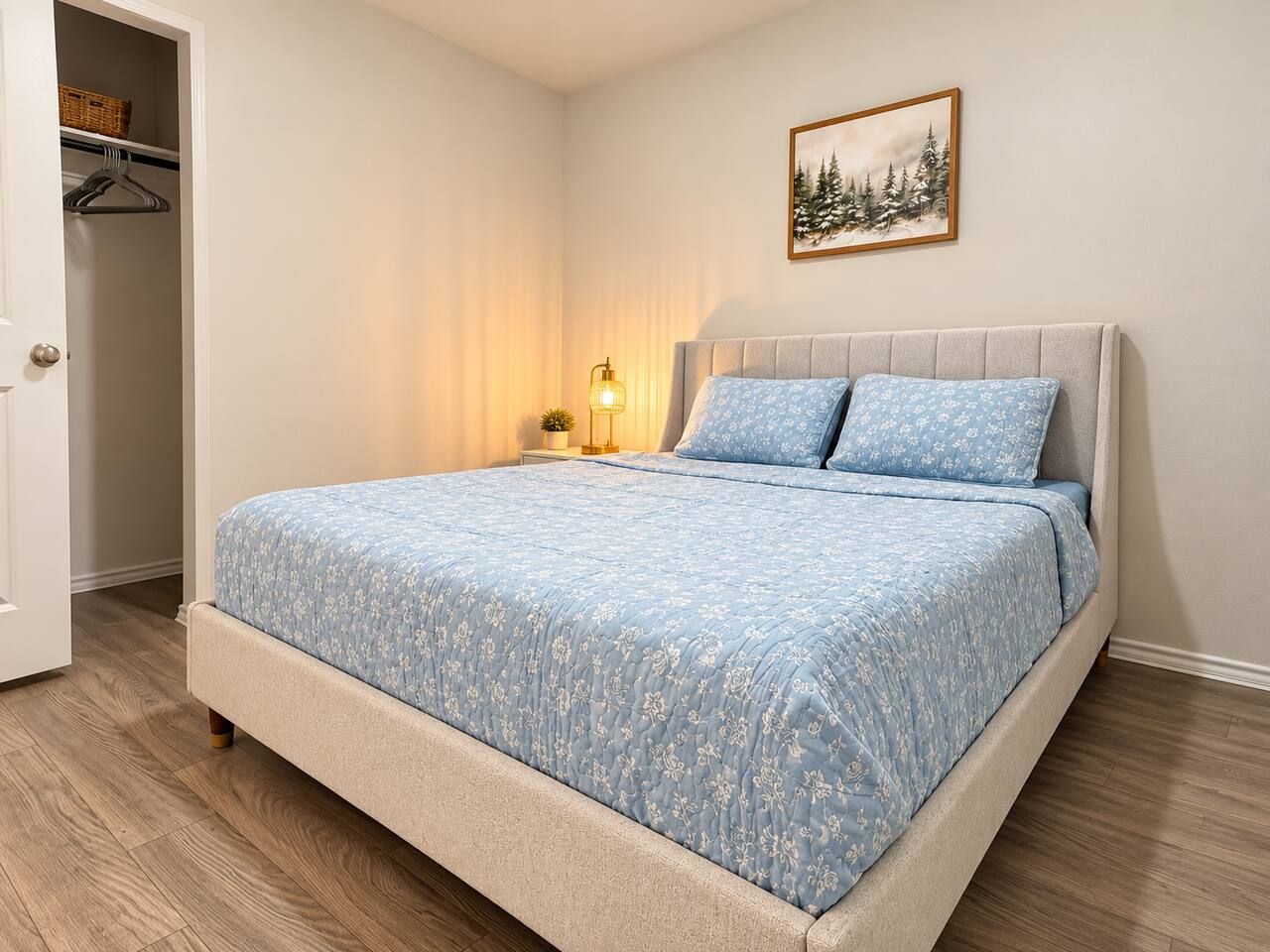 Una camera da letto con un letto, un comodino con una lampada, un armadio e un quadro appeso al muro.