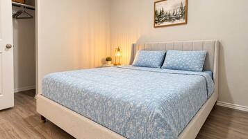 Una camera da letto con un letto, un comodino con una lampada, un armadio e un quadro appeso al muro.