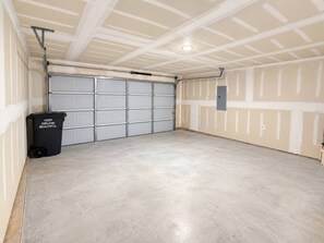A garage with a concrete floor, white walls, and a grey garage door. - Spacious 4BR Retreat | Near Dyess & Data Centers (Abilene)