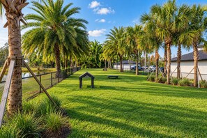 A well-maintained grassy area with palm trees, a small gazebo, and a fence. - 2BR Suite - Pool, Gym, Games & Dog Friendly (Middleburg)