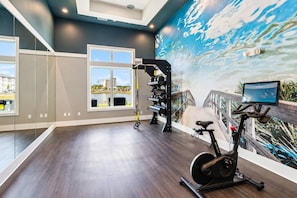 A modern gym with a large mirror, exercise equipment, and a scenic mural. - 2BR Suite - Pool, Gym, Games & Dog Friendly (Middleburg)