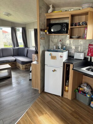 A compact kitchenette with a refrigerator, microwave, toaster, and a small sink. - 6Berth Caravan-Wheelchair Accessible-Pet Friendly (Skegness)