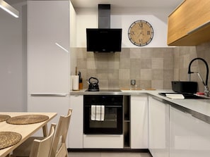 Een moderne keuken met een flatscreen televisie, een klok en een waterkoker op het aanrecht.