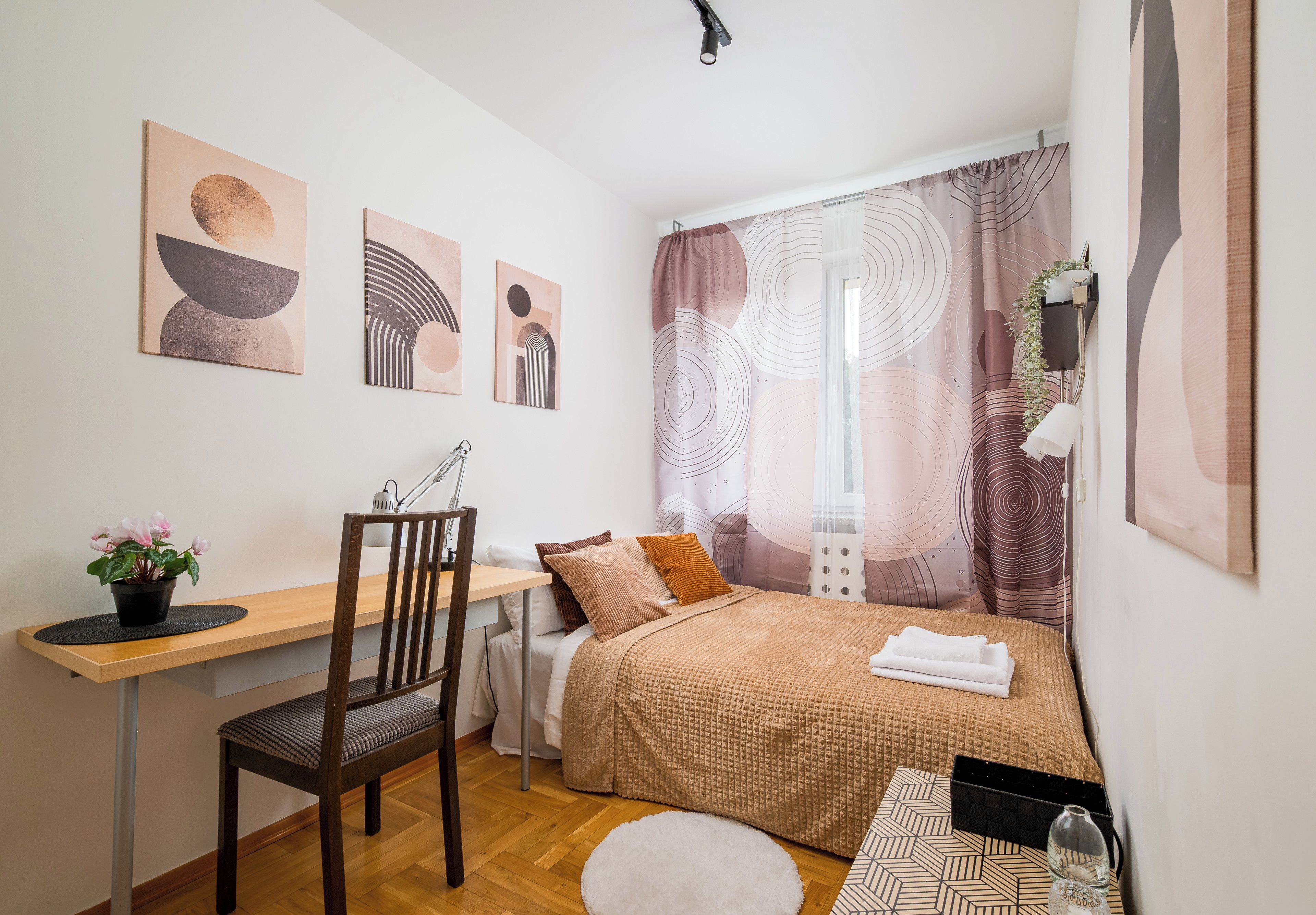 Ein Schlafzimmer mit einem Bett, einem Schreibtisch, einem Stuhl und einer Zimmerpflanze.