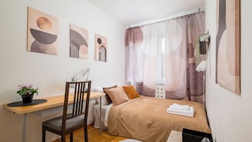 Ein Schlafzimmer mit einem Bett, einem Schreibtisch, einem Stuhl und einer Zimmerpflanze.