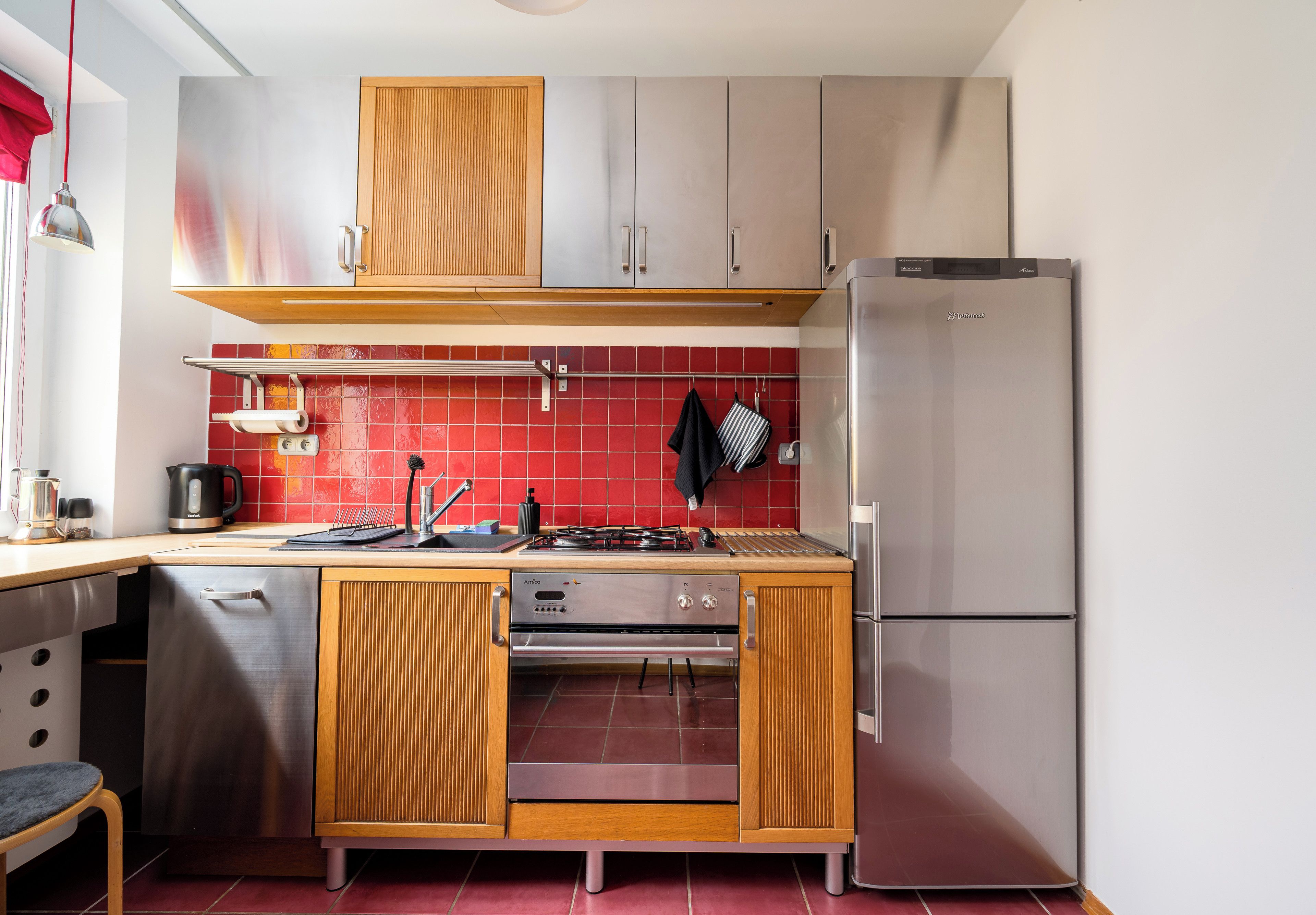 Una cucina compatta con fornello, forno e frigorifero.