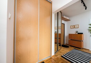 Une pièce avec une porte coulissante en bois, un meuble en bois doté de tiroirs, un tapis à rayures noires et blanches et une plante posée sur le sol.