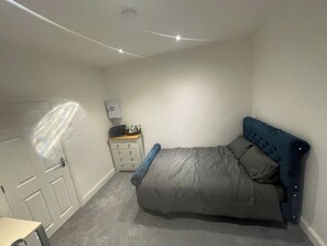 Quarto com cama, penteadeira, mesa de cabeceira e porta.