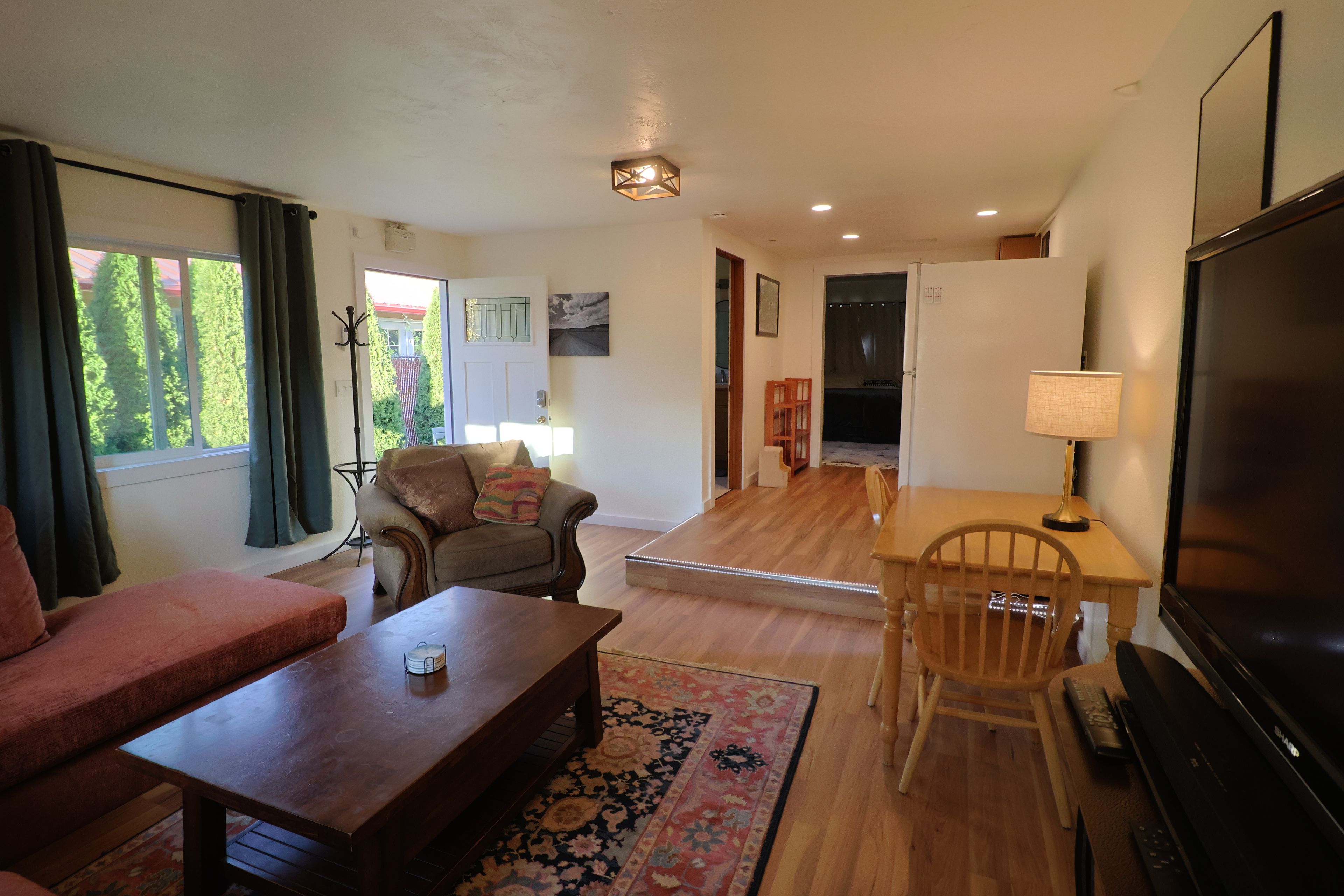 A living room with a sofa, a coffee table, a TV, and a dining area with a table and chairs.