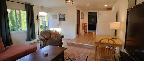 A living room with a sofa, a coffee table, a TV, and a dining area with a table and chairs.