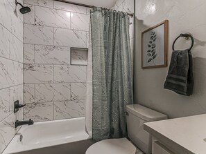 Een badkamer met een badkuip, toilet en douchegordijn.