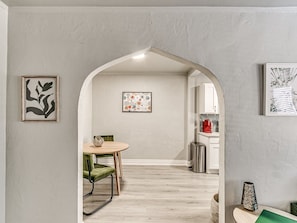Ein Zimmer mit Essbereich, einer durch einen Bogen sichtbaren Küche und Kunstwerken an den Wänden.