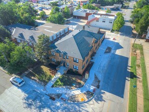 An aerial view of a multi-story building with a parking lot, surrounded by trees and other buildings. - Stylish Midtown OKC Condo (Oklahoma City)