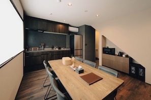A modern kitchen with dark cabinetry, a wooden dining table, and a built-in bench. - Maru  (Shimotakai-gun)