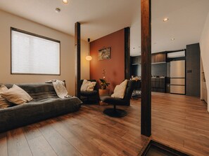 Una sala de estar moderna con un sofá, dos sillones, una mesita de centro y una planta en maceta.