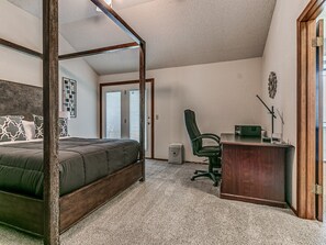 A bedroom with a four-poster bed, a desk, and a chair. - Modern OKC Home Near Lake Hefner (Oklahoma City)