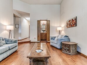 Una sala de estar con dos sofás, una mesa de centro y un aparador de madera.