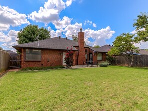 A brick house with a chimney, a fenced yard, and a satellite dish. - Modern OKC Home Near Lake Hefner (Oklahoma City)