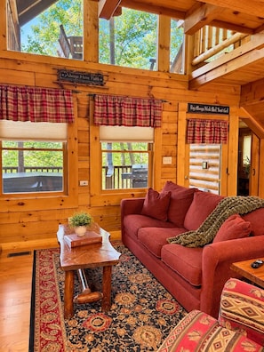 A cozy cabin interior with a red sofa, a wooden coffee table, and a patterned rug. - Cozy Cabin: Private Hot Tub, Fireplace & Mtn Views (Sevier County)