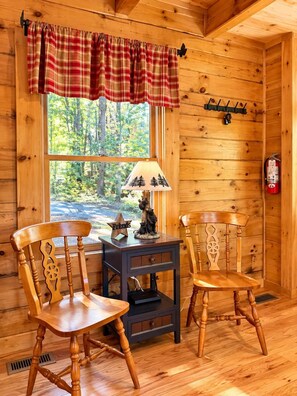 A cozy cabin interior with a plaid curtain, a lamp, a bear statue, and a fire extinguisher on the wall. - Cozy Cabin: Private Hot Tub, Fireplace & Mtn Views (Sevier County)