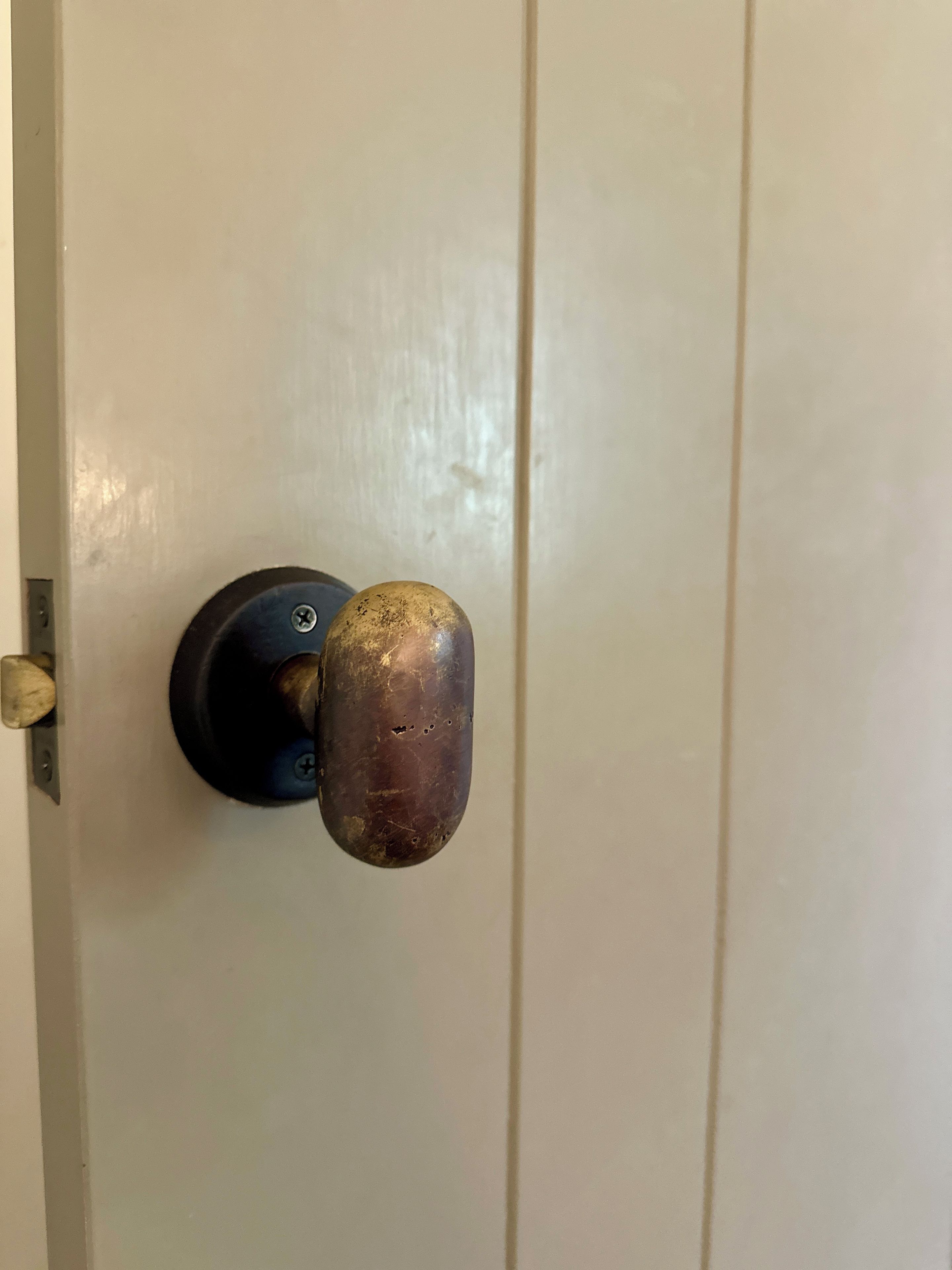 Una puerta con un pomo metálico redondo y una cerradura.