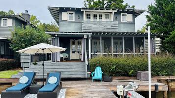 Een twee verdiepingen tellend huis met een overdekte veranda en een houten terras.