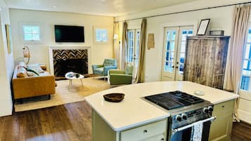 Una cucina con isola centrale, piano cottura integrato e zona pranzo con divano e sedie.