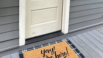 A front door with a glass panel, a doormat with text, and a window above the door.