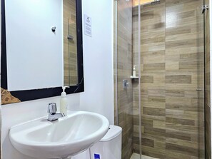 A bathroom with a white sink, a mirror, and a shower area with wooden flooring. - 110 Loft Granada (Cali)