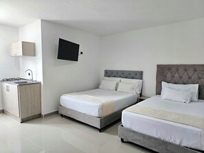 A hotel room with a kitchenette, a bed with a tufted headboard, and a flat-screen TV mounted on the wall. - 110 Loft Granada (Cali)