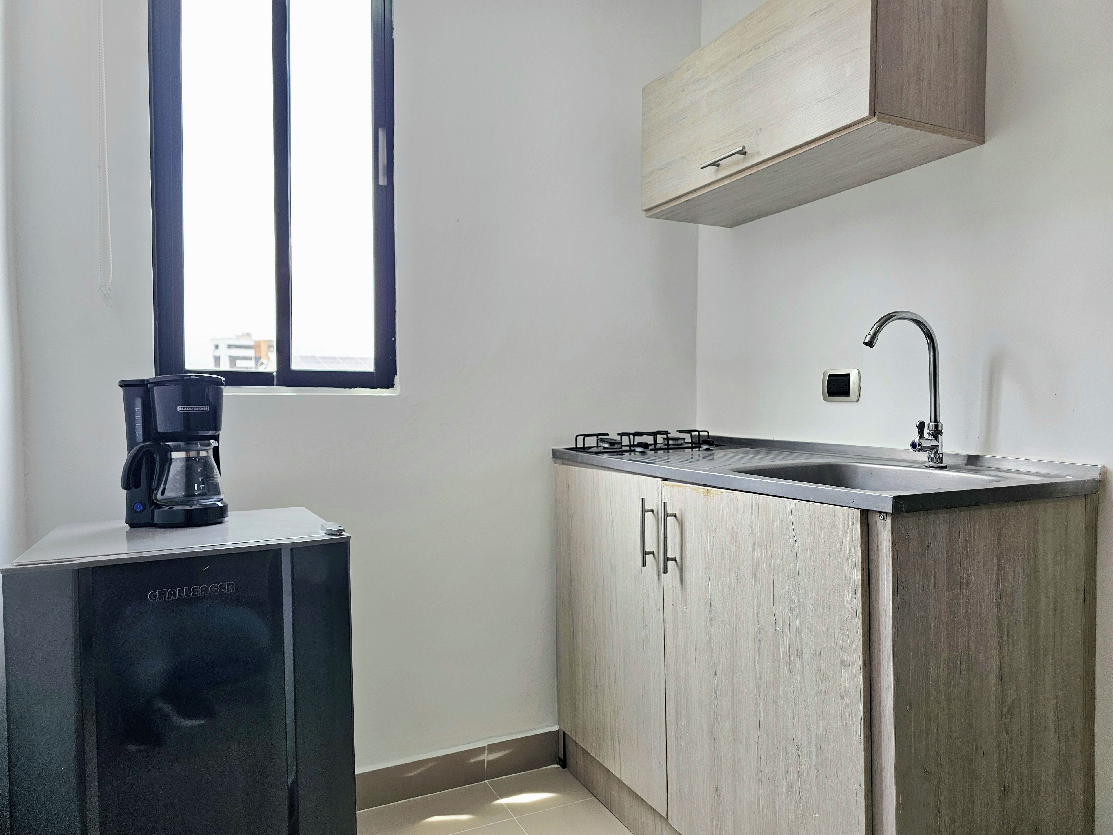 A compact kitchen with a coffee maker, a gas stove, and a sink.