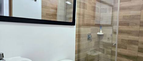 A bathroom with a glass-enclosed shower, a white sink, and a toilet.