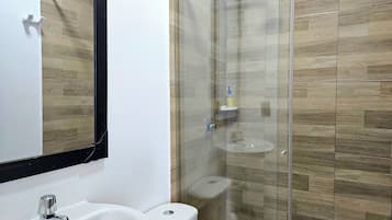 A bathroom with a white sink, a toilet, and a glass-enclosed shower area.