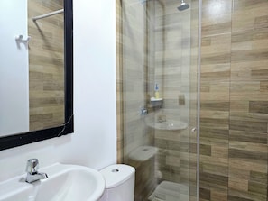 A bathroom with a white sink, a toilet, and a glass-enclosed shower area. - 110 Loft Granada (Cali)