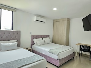 Habitación de hotel con dos camas, un armario, un escritorio y un equipo de aire acondicionado.