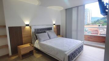 Un dormitorio moderno con cama, mesitas de noche y vistas a la ciudad.