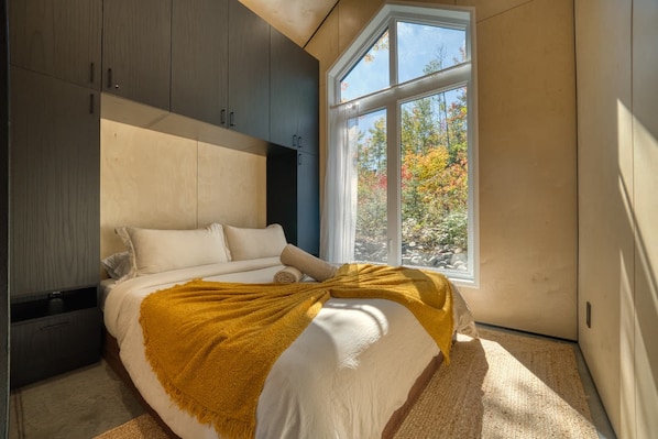 A bedroom with a bed, a window, and built-in cabinets. - Spa & Mountain - Cabine Kuro (Adstock)