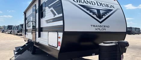 Una caravana Grand Design Transcend Xplor estacionada en un estacionamiento.