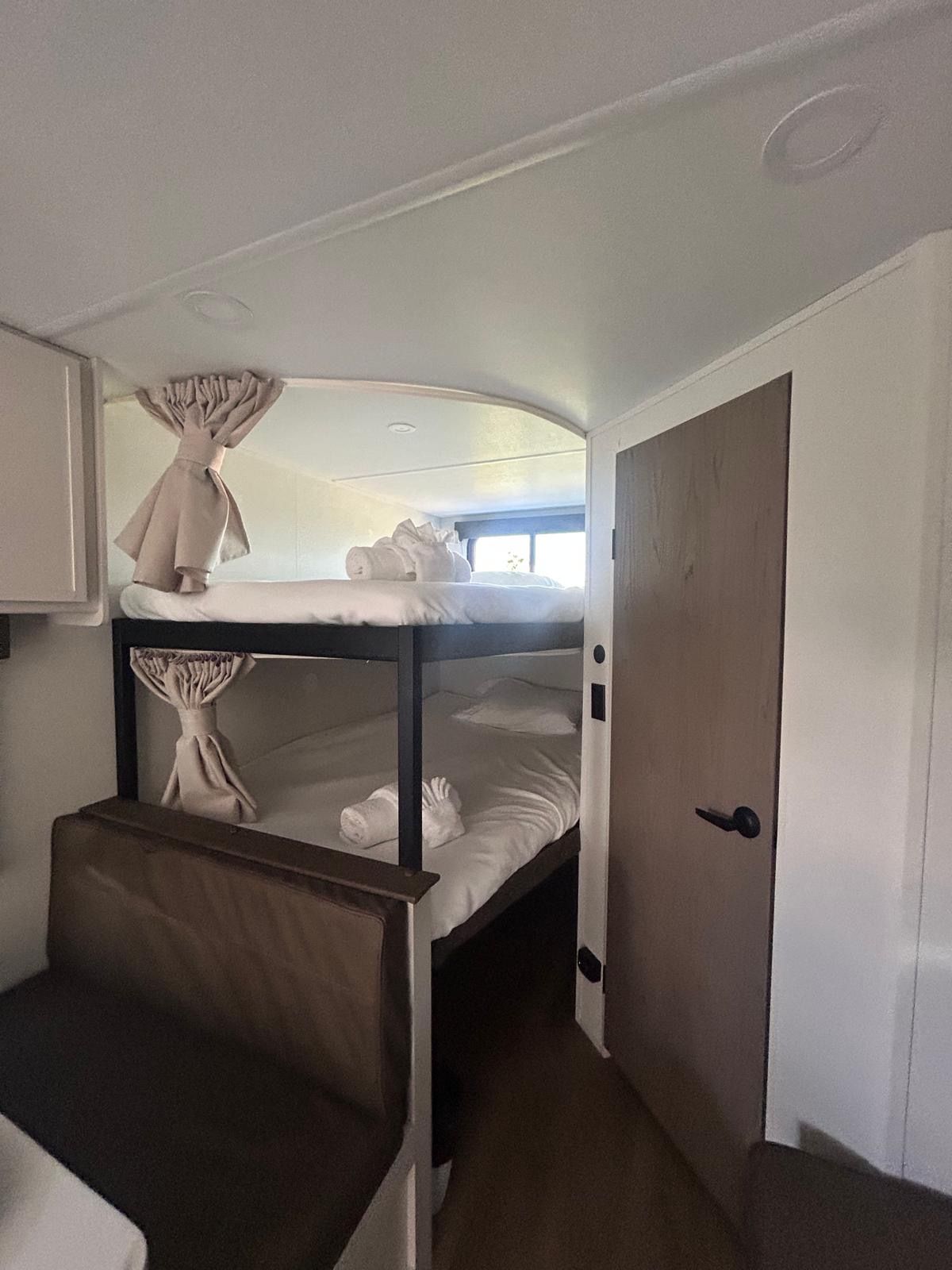 Una camera con un letto a castello, una porta e una piccola finestra.