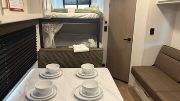 Cocina compacta con una mesa dispuesta para cuatro personas, una litera y una zona de estar.