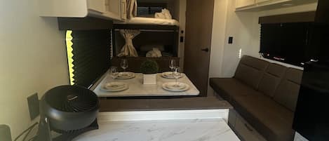 A compact kitchenette with a marble countertop, a built-in oven, and a seating area with a sofa.