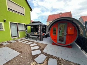 A green building with a covered patio area, a circular structure with a door, and a paved walkway with stepping stones. - Vacation Rental Near Rothenburg / Romantic Franconia (Colmberg)