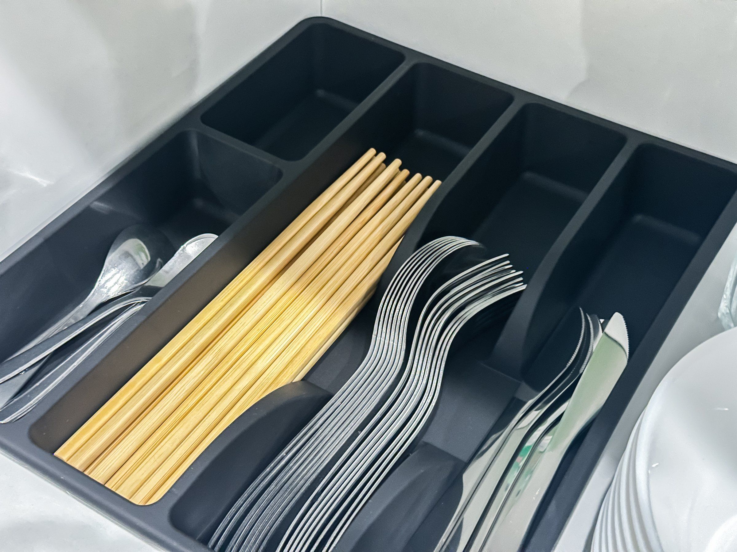 A compartmentalized storage unit with utensils and cutlery.