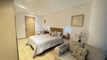A bedroom with a bed, a sofa, a desk, and a chair.
